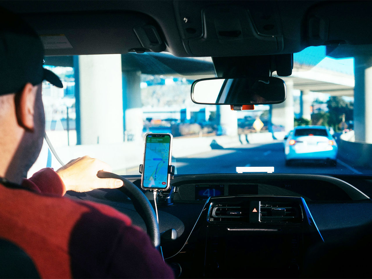 An image of a driver from the back seat of a car