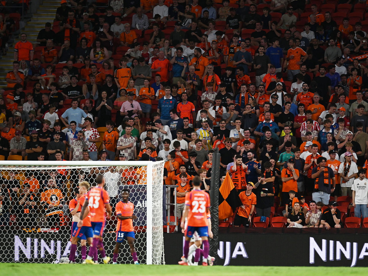 The Brisbane Roar ready to defend a cross with the Den supporters in the background