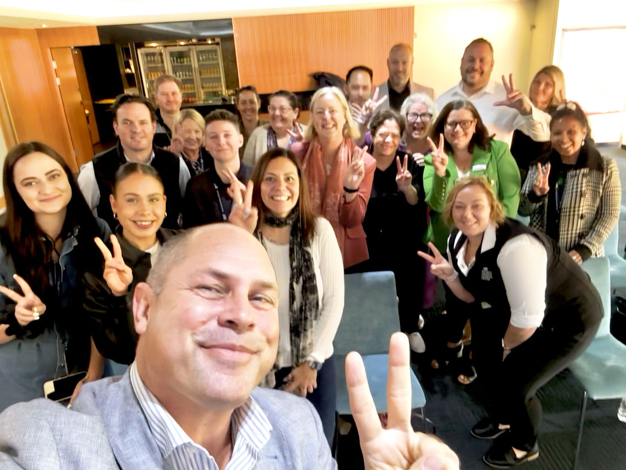 Suncorp Stadium team and ASM Global First Nations Ambassador Cameron Costello smiling at the camera and making peace signs.