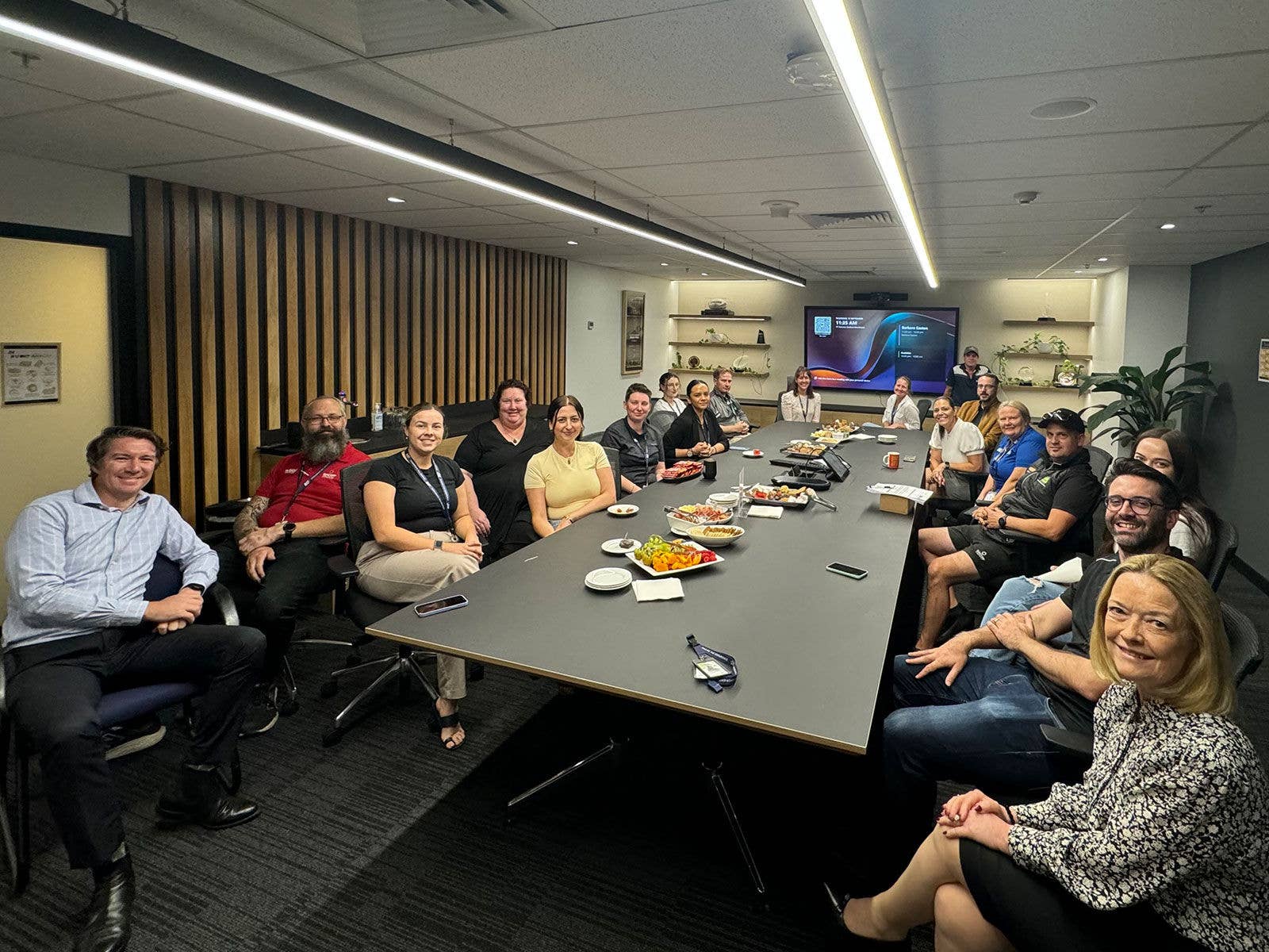 Suncorp Stadium permanent staff members sat around a boardroom table, sharing morning tea.