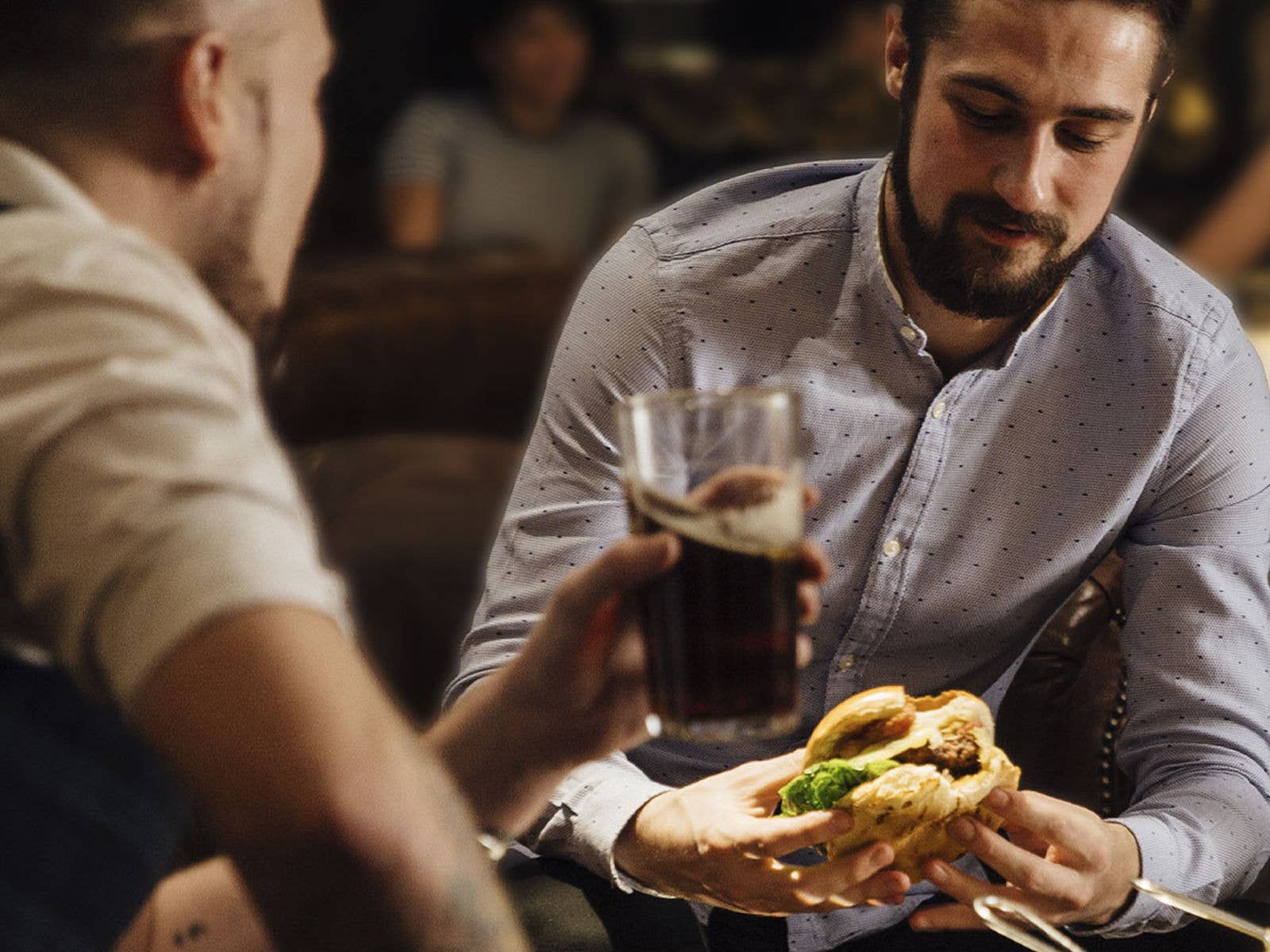 Two people enjoying a burger and a drink together