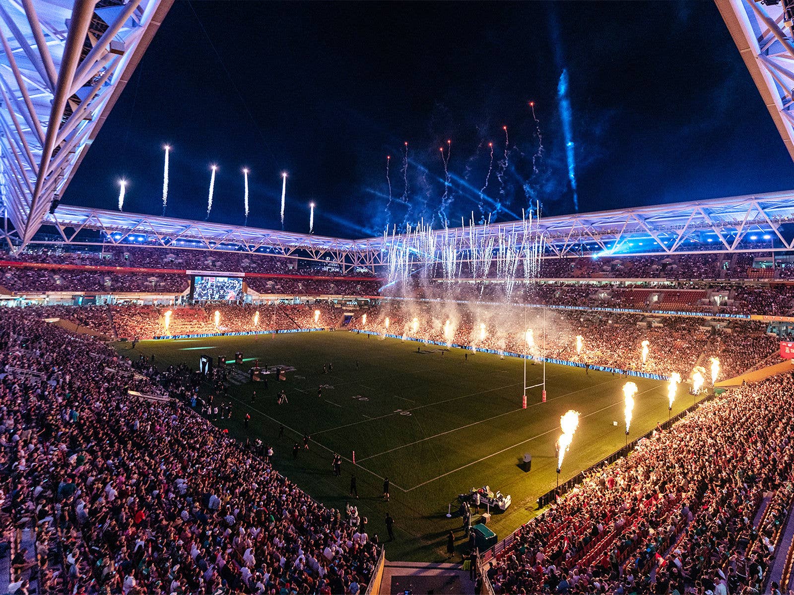 Internal view of Suncorp Stadium during a night time event. Fireworks and pyrotechnics are happening on the field.