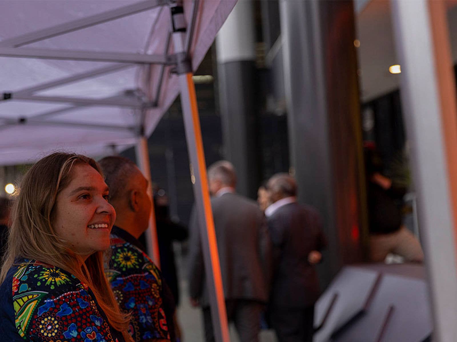 Patron looking at 'Welcome' artwork. Person stood under gazebo looking and smiling at 'Welcome' artwork.