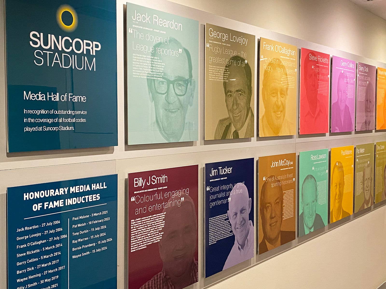 Various coloured Suncorp Stadium Media Hall of Fame plaques against a plain wall. 