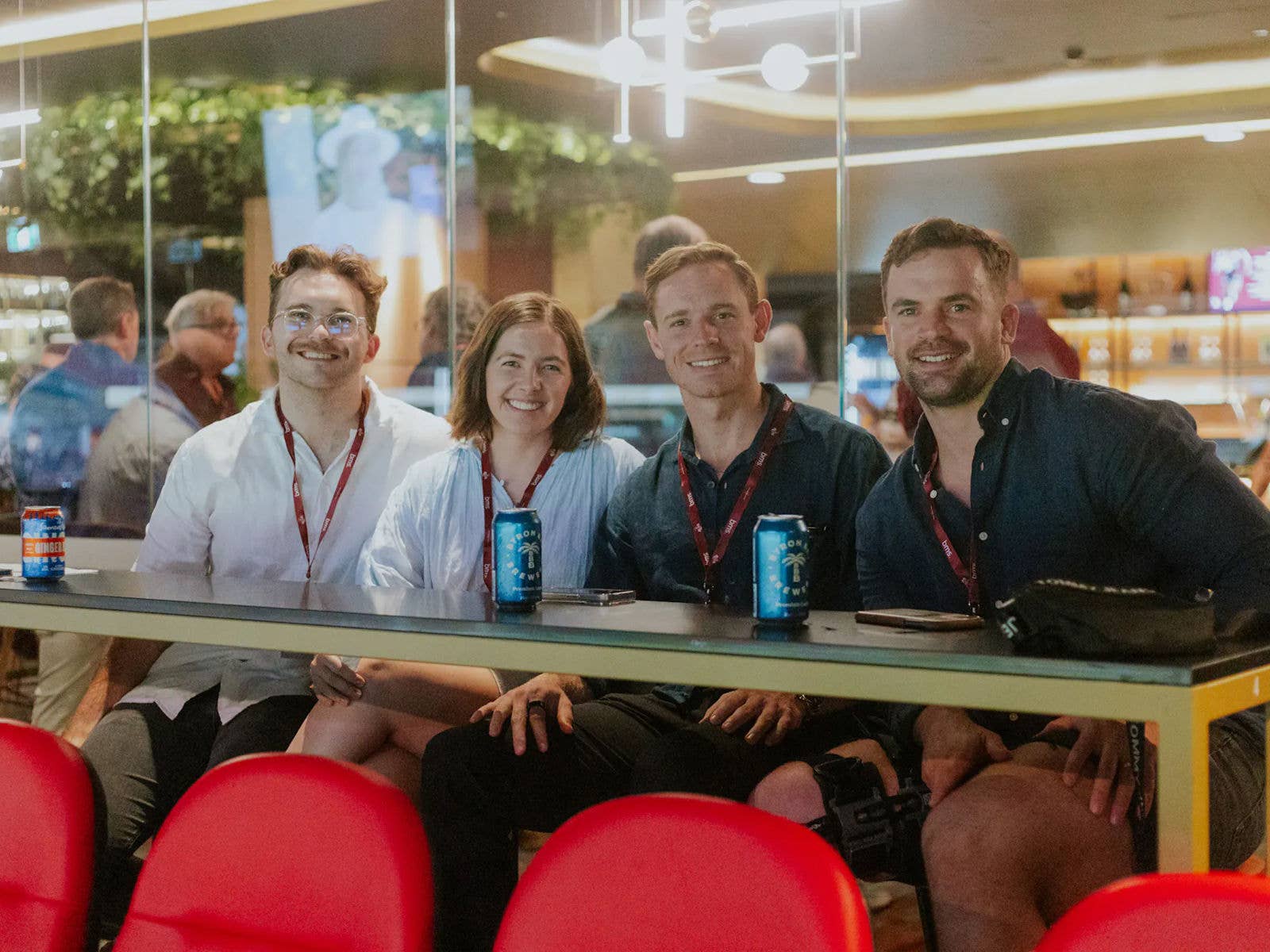 Four patrons smiling at the camera. Sat in a corporate hospitality area, wearing lanyards.