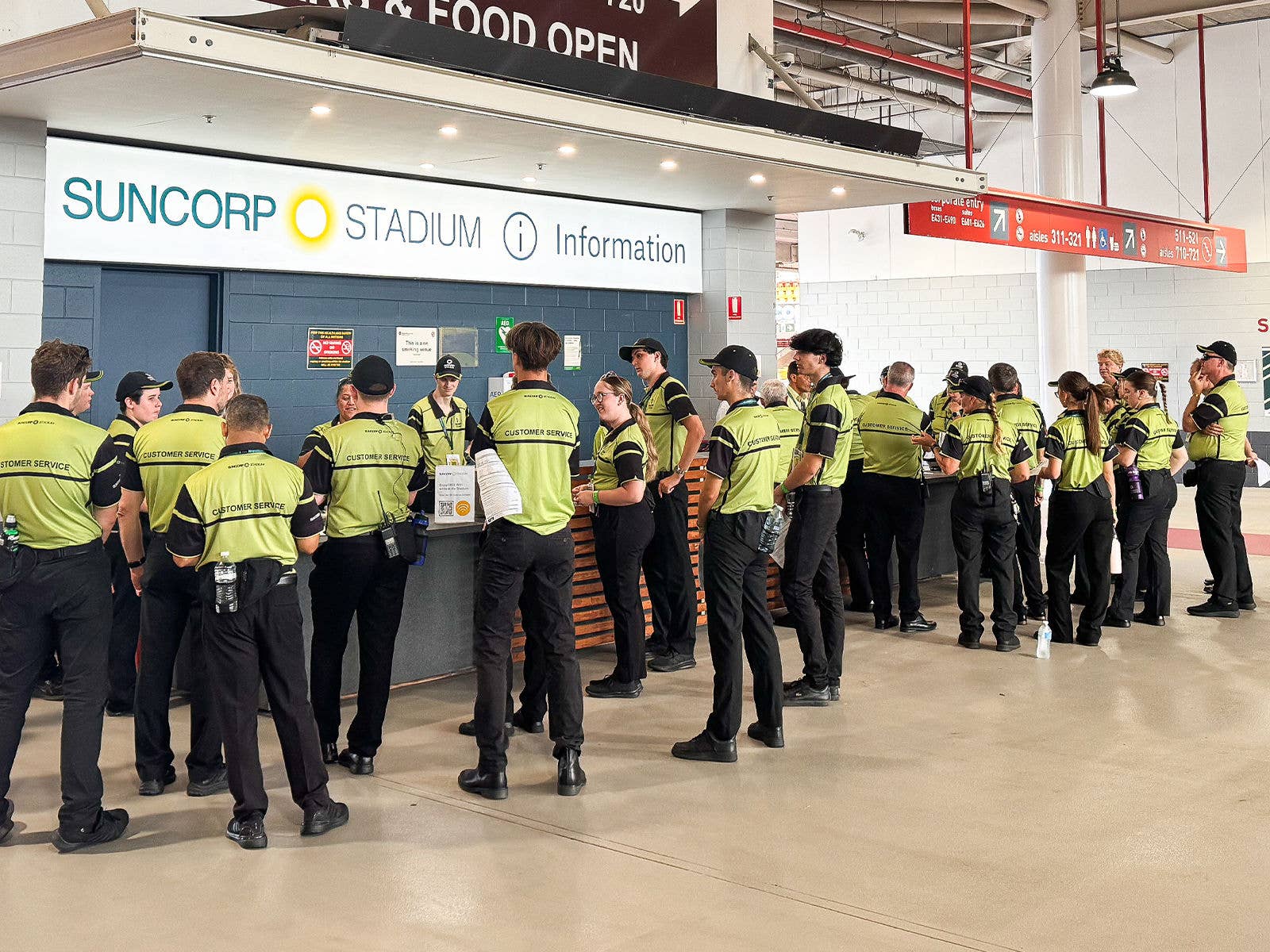 Suncorp Stadium event staff standing in a huddle at the information desk
