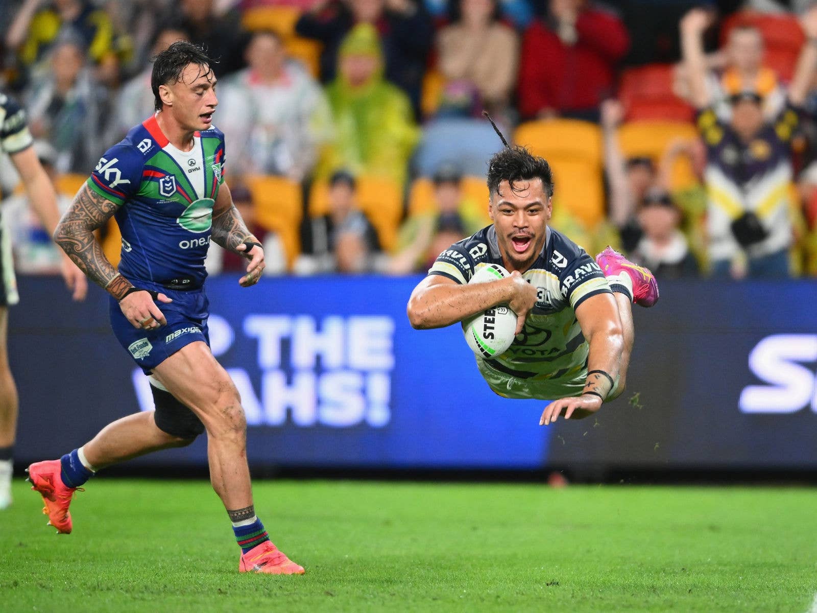 A warriors player sad as a Cowboys player scores a try during Magic Round