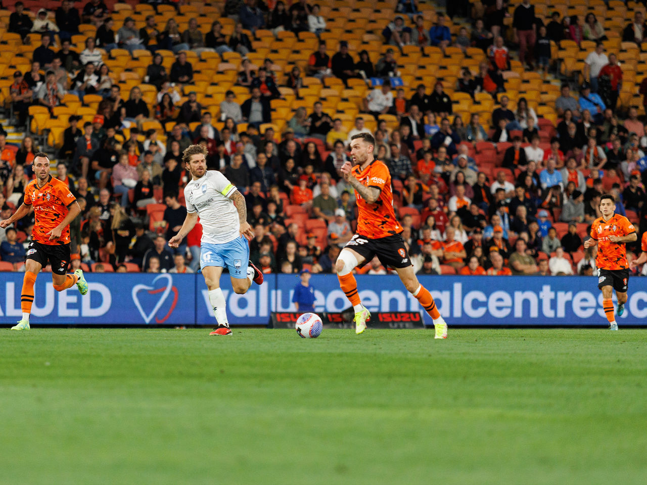 Image of Brisbane Roar player dribbling football on Suncorp Stadium field.