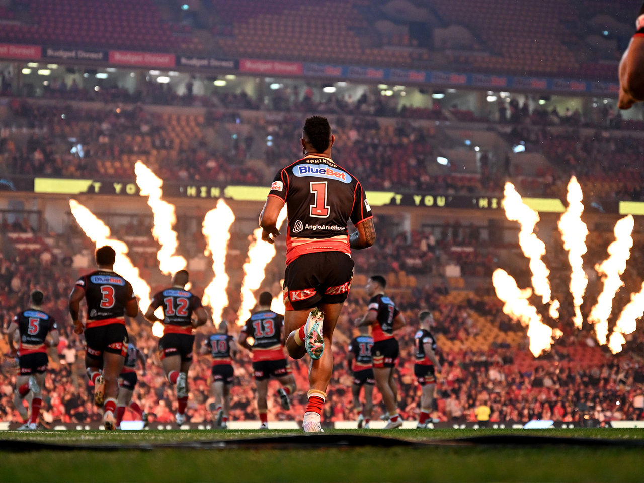 Dolphins players run out onto the Suncorp Stadium pitch as a pyrotechnic display goes off