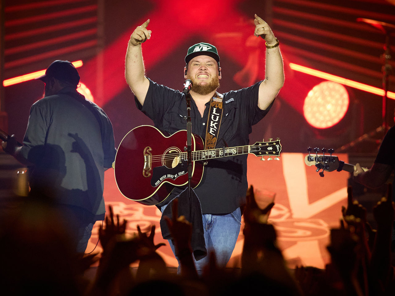 Luke Combs on stage with his guitar in front of a crowd