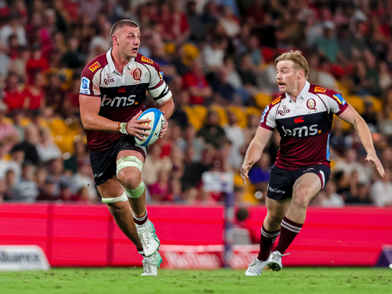 Reds player Josh Canham running with the ball alongside teammate Harry McLaughlin-Phillips