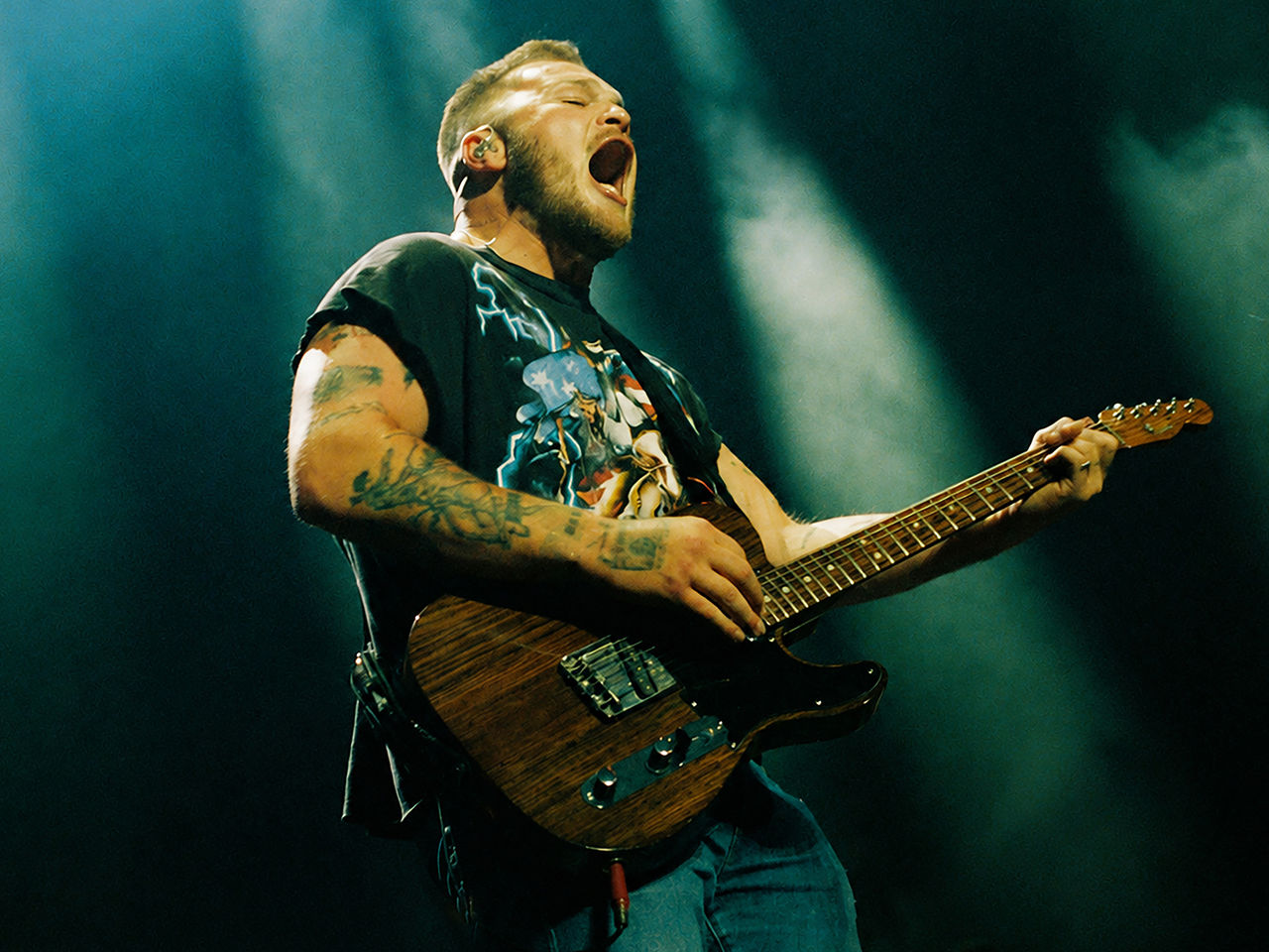 Zach Bryan singing and playing guitar on stage