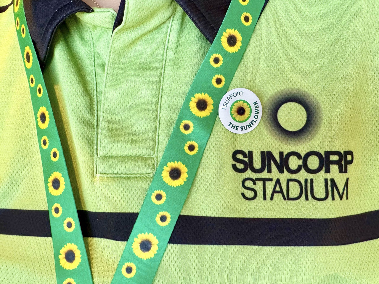 A Suncorp Stadium event staff members shirt with a sunflower lanyard and a badge saying I support the sunflower